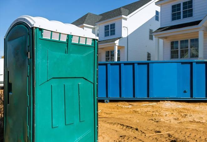 a row of blue and white porta potties on a busy construction site